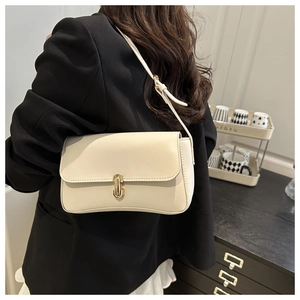 Model wearing a cream rectangle shoulder bag with a gold metal lock and leather strap