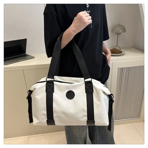 Detail of white Oxford travel bag featuring black circular logo and wide carry straps
