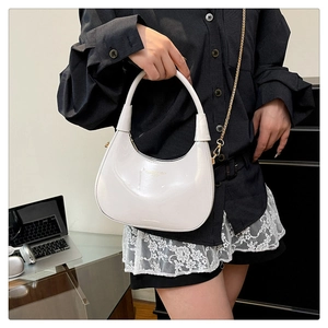 Detail showing the glossy white crescent bag with golden chain strap and logo