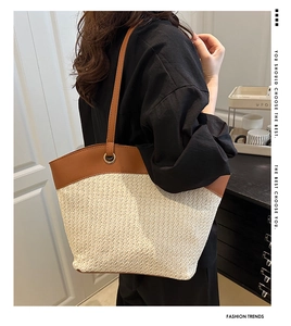 Close-up of a French retro straw tote bag with brown leather straps on a model's shoulder