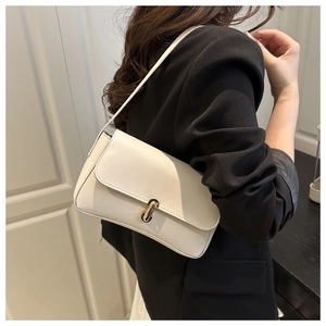 Detail of cream white faux leather underarm bag featuring a golden cylindrical twist lock