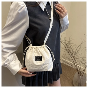 Detail of white drawstring bucket bag showing F FANVISSA label and textured nylon material