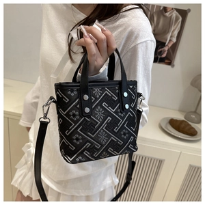Detailed shot of fabric bucket bag with silver geometric embroidery and leather handles