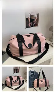 Detailed view of pink waterproof nylon travel bag with black straps and logo detail