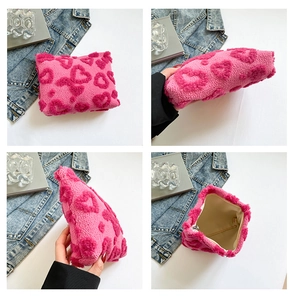 Vista dettagliata di una borsa cosmetica in peluche rosa con morbidi motivi a cuore