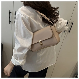 Detailed view of the adjustable strap and golden cylinder buckle on a beige leather bag