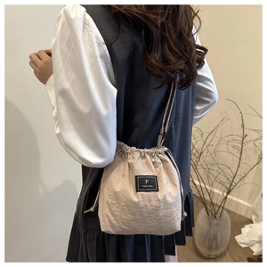 Detail of minimalist nylon drawstring bucket bag with branded label and cord strap