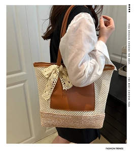 Detail of beige straw tote bag with brown leather trim and a lace bow decoration