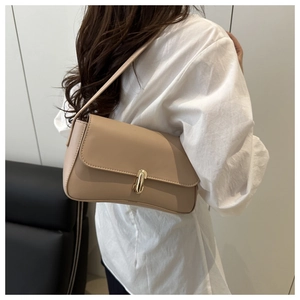 Side view of an apricot faux leather baguette bag with gold buckle on a model shoulder