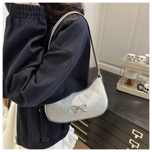 Silver sequin crescent shoulder bag with metallic bow detail worn by model
