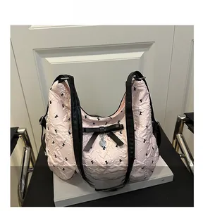 Détail du sac hobo matelassé rose avec broderie d'oiseaux et pendentif en forme de cœur
