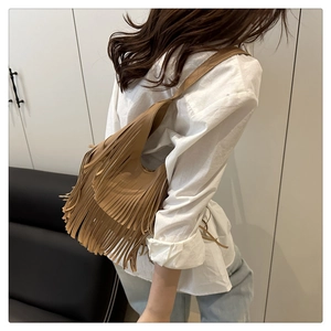 Vista trasera de una mujer con un bolso de hombro de cuero caqui con flecos estilo boho