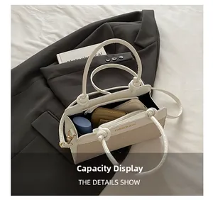 Internal capacity of minimalist cream shoulder bag showing phone and cosmetics