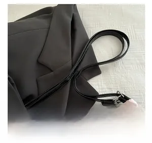 Détail du sac cabas en tissu rose texturé avec bandoulière noire et boucles argentées