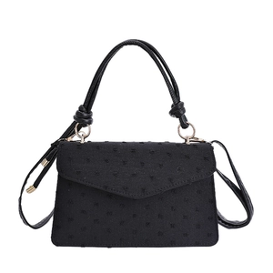 Élégant petit sac à bandoulière noir texturé avec sa poignée supérieure nouée