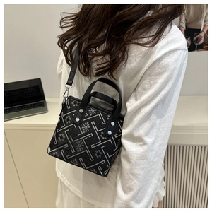 Close-up of black and white geometric embroidery and metal studs on the handbag