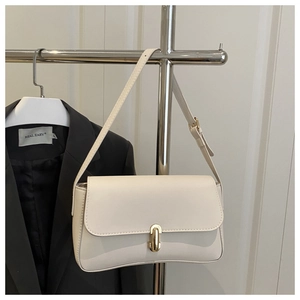 Detail of cream rectangular shoulder bag with golden capsule-shaped metal twist lock closure