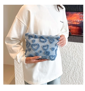 Close-up view of a cute light blue plush handbag with textured blue heart patterns