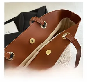 Detailed view of straw tote with gold magnetic clasp and premium brown leather handles