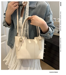 Creamy white bucket bag in lychee texture leather held by a model in a home setting