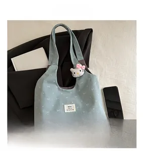 Detail shot of light blue denim tote with white bow patterns and Hello Kitty plush charm