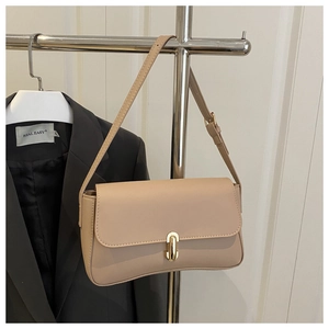 Detail of minimalist beige underarm bag with elegant gold cylindrical buckle closure