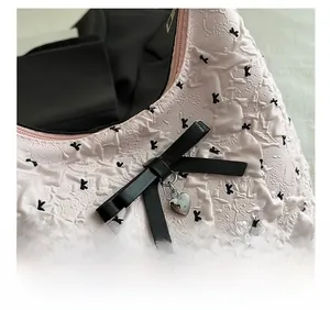 Détail du tissu gaufré rose avec nœud noir et pendentif en forme de cœur argenté