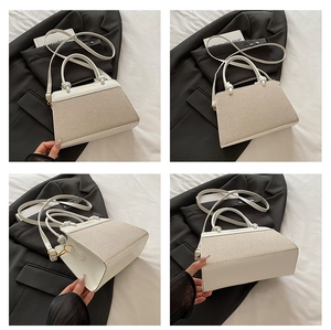 Detail view of beige canvas tote bag with white leather trim and gold metal hardware
