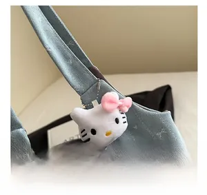 Detail showing light blue denim texture tote bag with white plush kitty charm on the strap