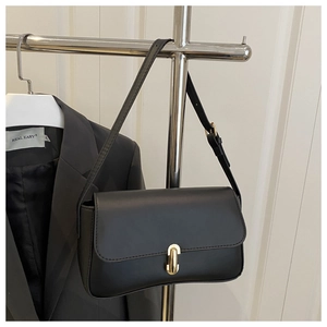Detail of minimalist black leather underarm bag with elegant gold U-shaped twist lock