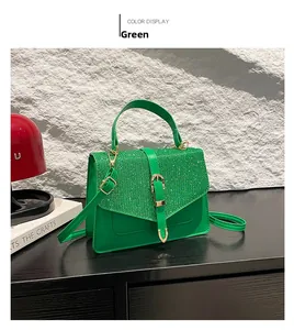 Détail du sac bandoulière vert avec paillettes et boucle dorée sur table en bois