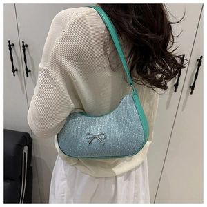Close-up of glittery crescent bag with silver bow accent and mint green contrast trim