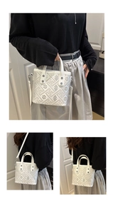 Detail of white bucket bag with floral embroidery and detachable silver shoulder straps
