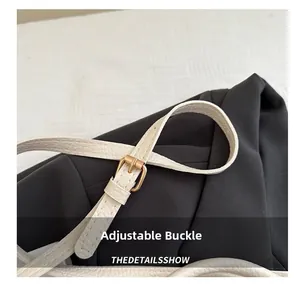 Detail view of adjustable gold buckle and off-white lychee grain leather strap