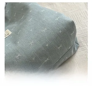Macro detail of high-quality cross-stitch embroidery on light blue-grey canvas tote bag
