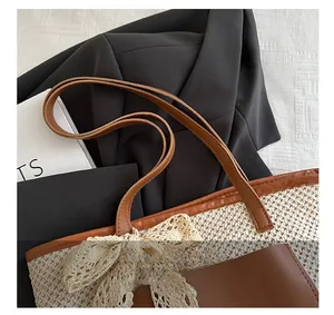 Detail of woven straw tote bag with brown leather handles and a delicate lace bow accent