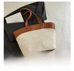 Detailed top view of large straw tote bag with brown leather trim and metal ring hardware