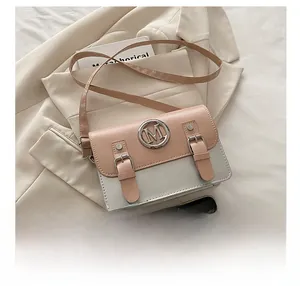 Detail of a pink and grey crossbody bag with round M metal logo and buckle accents