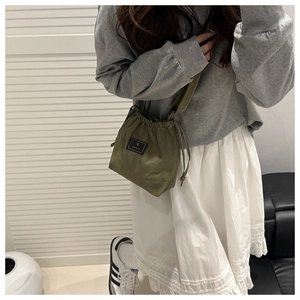Macro detail of dark green nylon bucket bag with drawstring closure and square woven label
