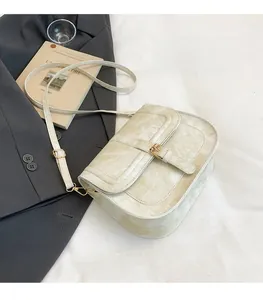 Detail view of cream saddle bag on suit with golden metal buckle and soft brushed fabric