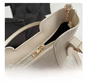 Close-up of smooth gold zipper and pebble leather texture on a modern tote bag