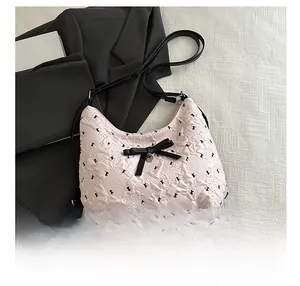 Détail du cabas matelassé rose avec nœuds noirs et pendentif cœur sur le tissu
