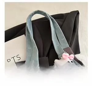 Detail of denim shoulder strap with bow embroidery and Hello Kitty plush pendant