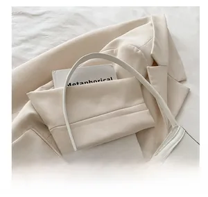 Detail of a creamy white handbag featuring a stylish metal bow buckle on textured leather