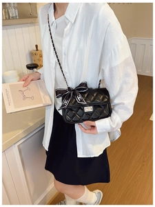 Detail of black quilted leather shoulder bag with golden clasp and silk scarf accessory