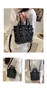 Detail view of jacquard pattern and silver rivets on the handle of a black tote bag