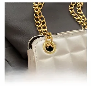 Détail du sac bandoulière ivoire matelassé avec chaîne dorée et œillets renforcés