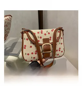 Détail du sac à bandoulière en toile avec imprimés cerises et boucle en métal doré