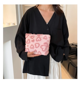 Close-up detail of a pink plush heart pattern pouch held by model for daily storage