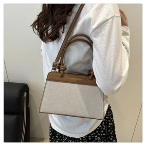 Detail view of contrast stitching and textured woven panel on luxury crossbody bag
